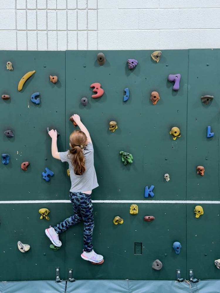 Students on rock wall in PE