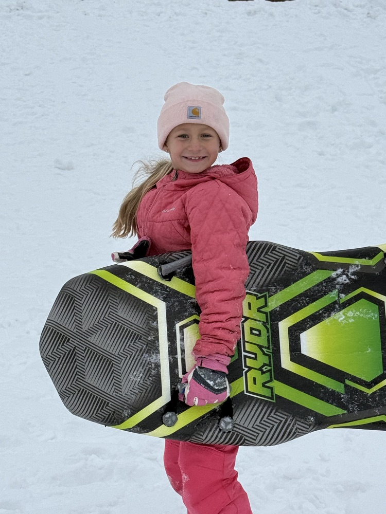 student smiling with sled