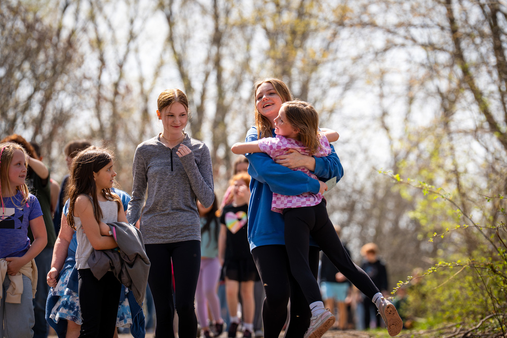 High school student hugging elementary student