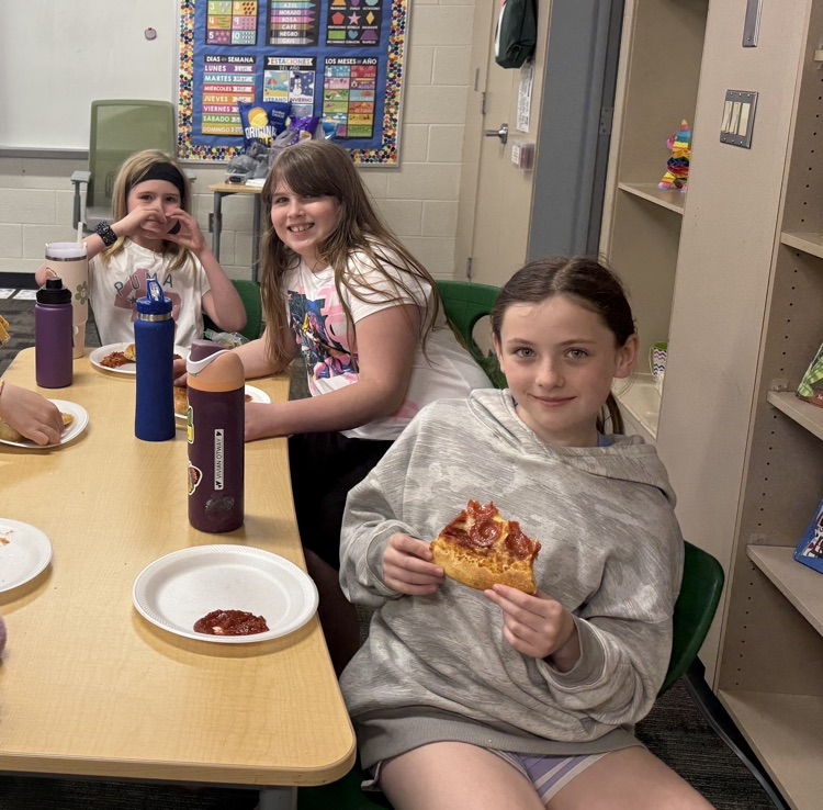 students smiling and eating pizza