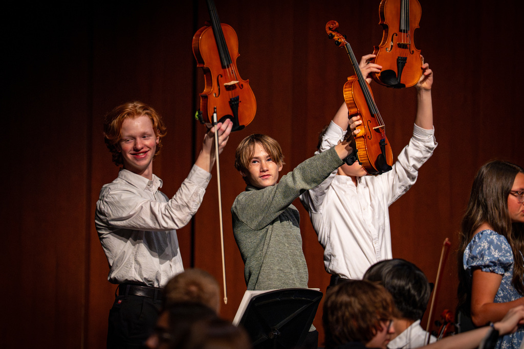 Orchestra students holding up their instruments