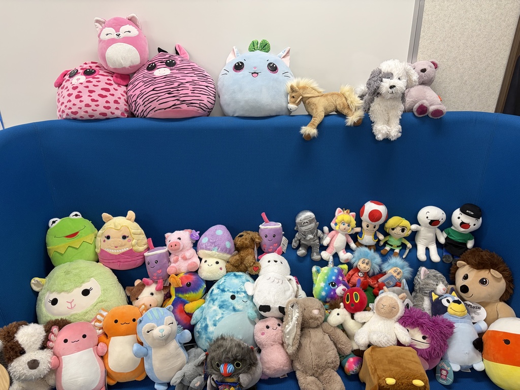 A variety of stuffed animals are displayed on a blue chair.