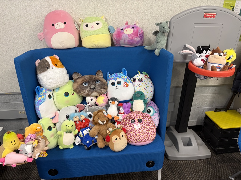 A variety of stuffed animals are displayed on a blue chair.