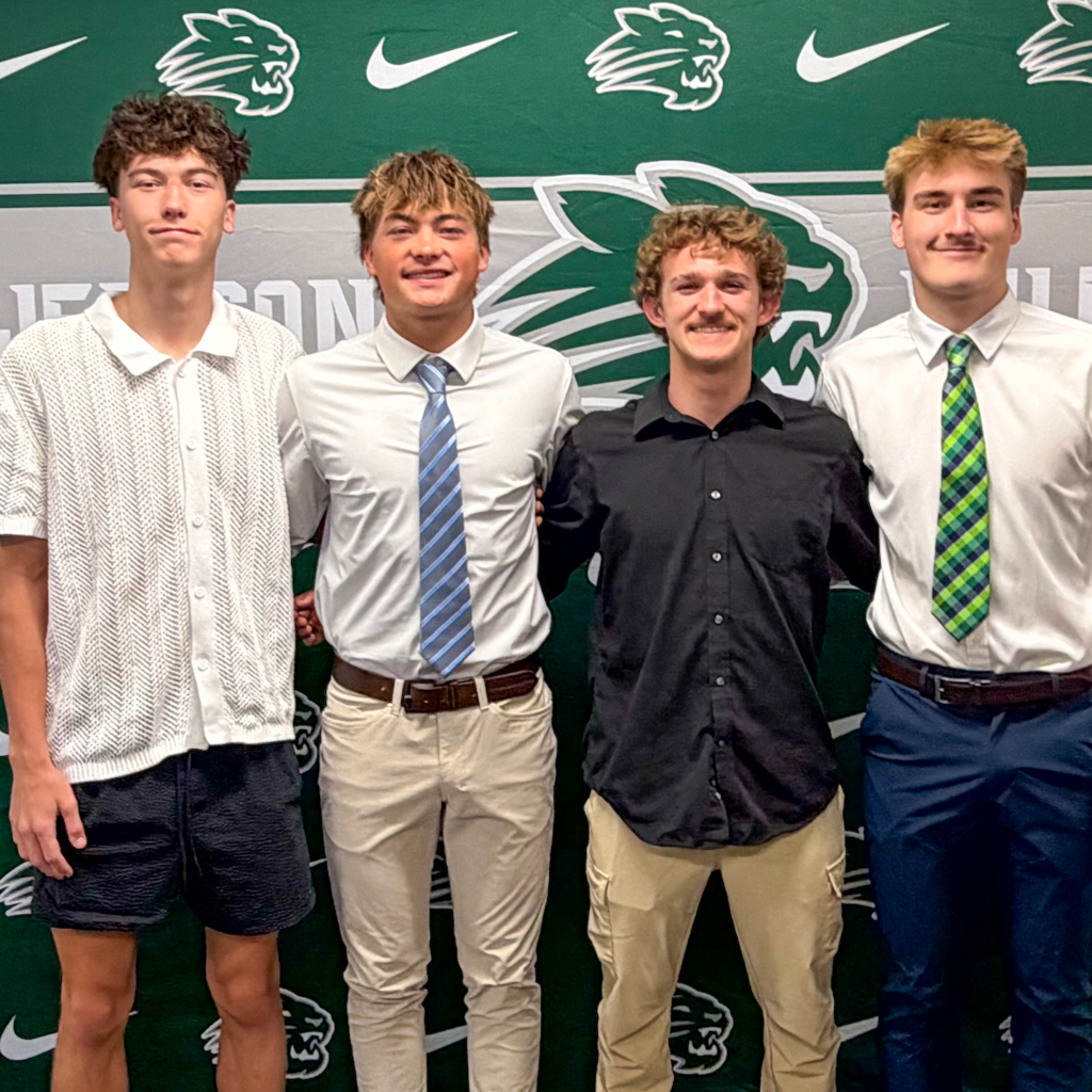 Boys volleyball team members posing in front of Wildcats backdrop