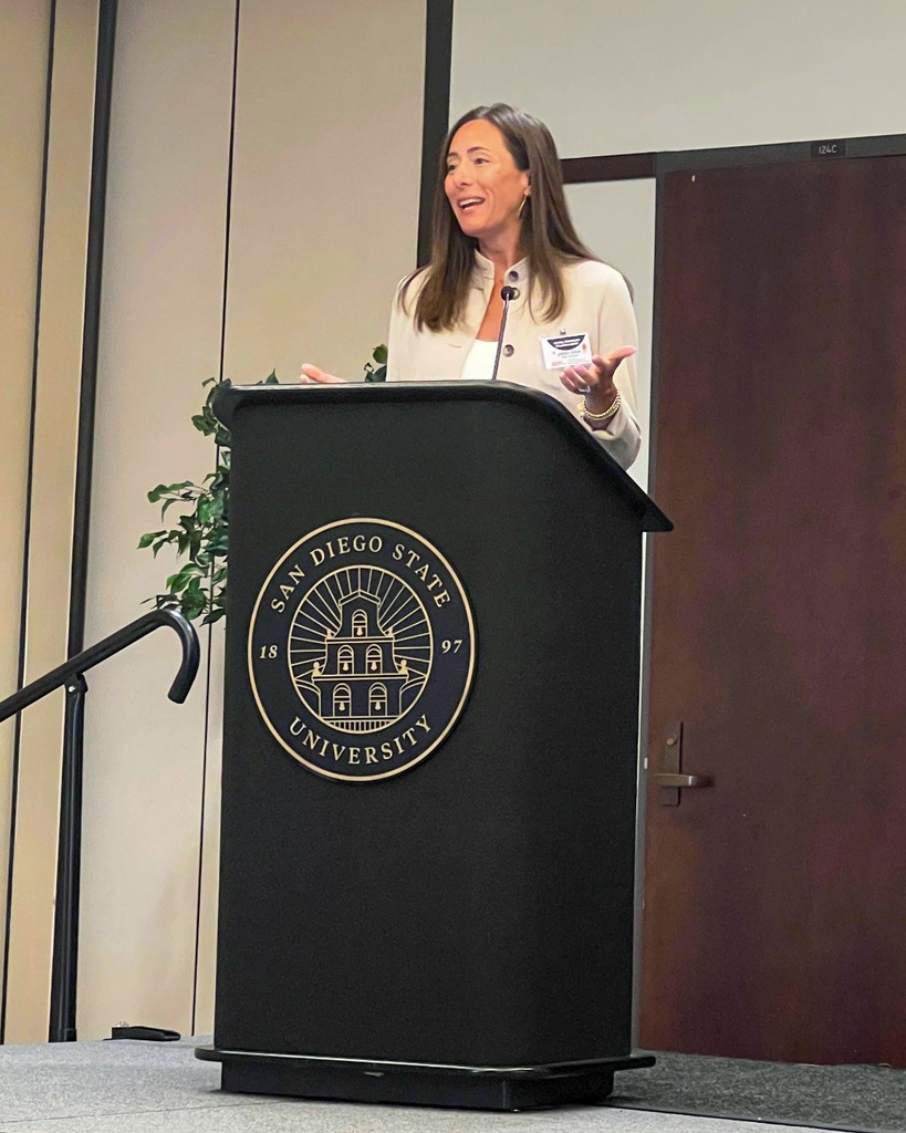 Jenny Riha speaking at podium in San Diego, California 