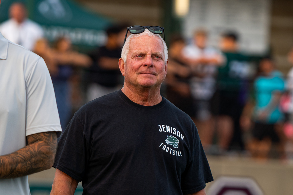 Former football coach smiling at game
