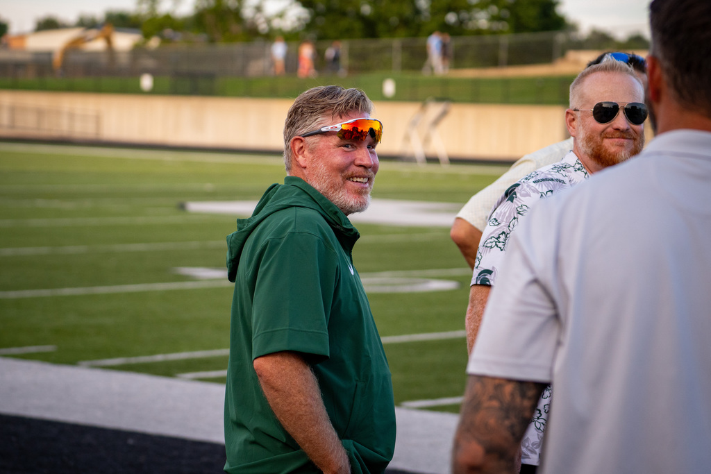 Former football players smiling at game