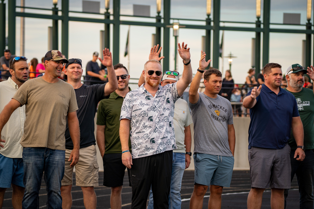 Former football players smiling and waving at game