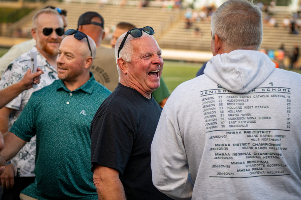 Former football coach smiling at game