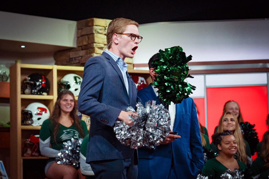TV host cheering with pom poms