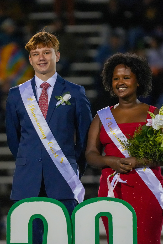 Homecoming reps wearing sashes, standing together, smiling, holding flowers.