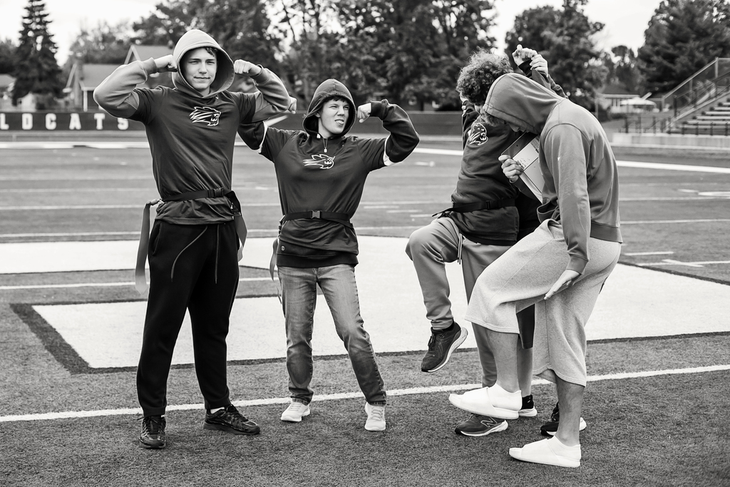 Four individuals in athletic attire on a field, one person crouched, another with bent knees, others standing upright.