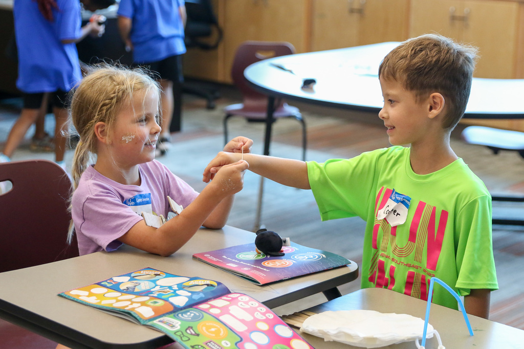 girl and boy smiling playing with crafts