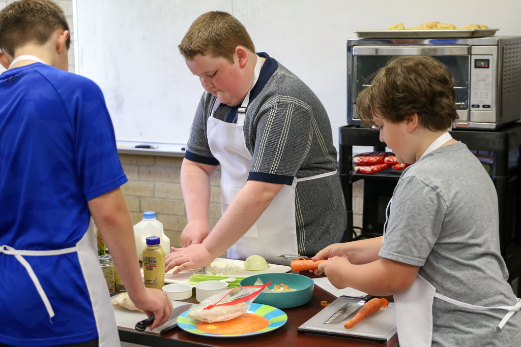 group of boys prepping veggies and chicken