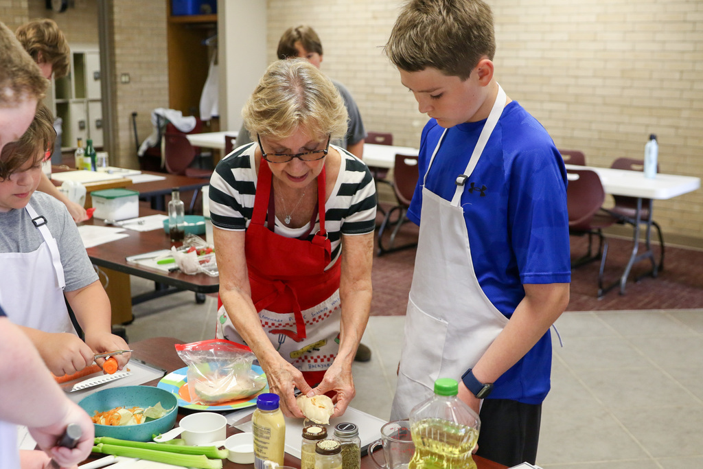 Teacher helping student chop chicken