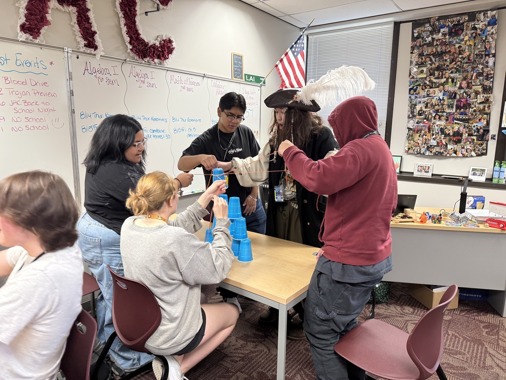 A photo of students working together to build a tower out of cups