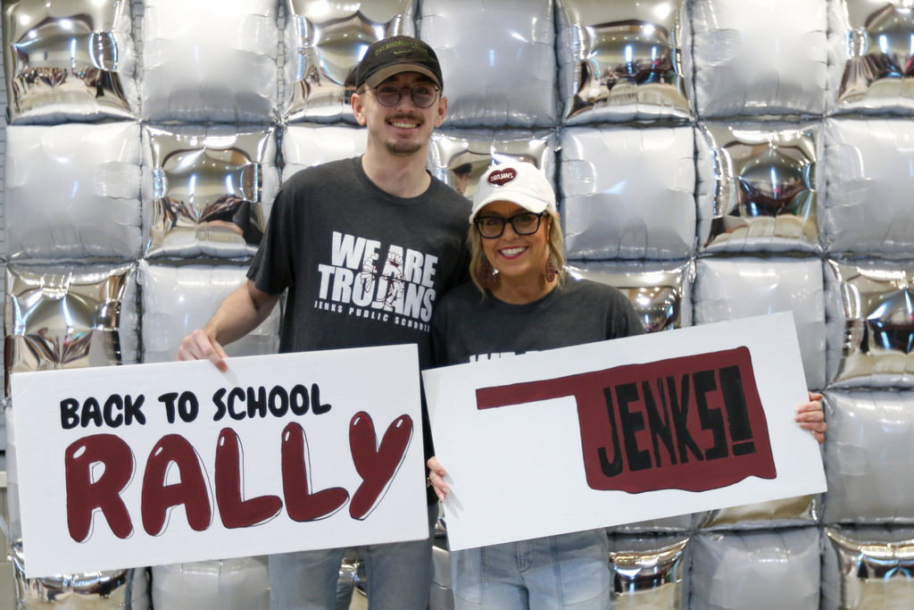 two people holding signs up that say back to school rally and henks infront of a balloon wall
