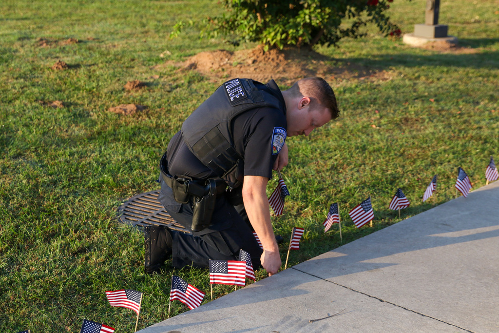 a Jenks police officer putting a flag in the ground