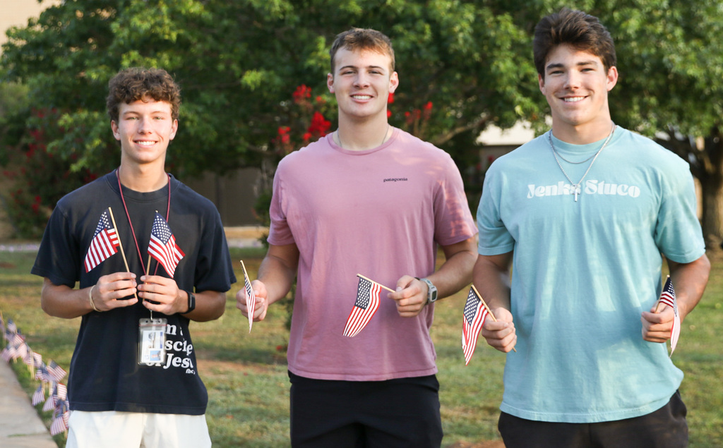 3 students pose for a photo with flags