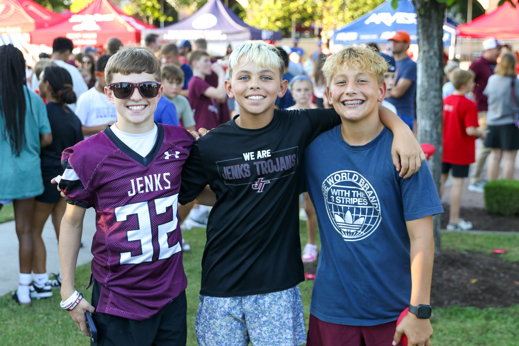 3 boys pose for photo with their arms on each others shoulders