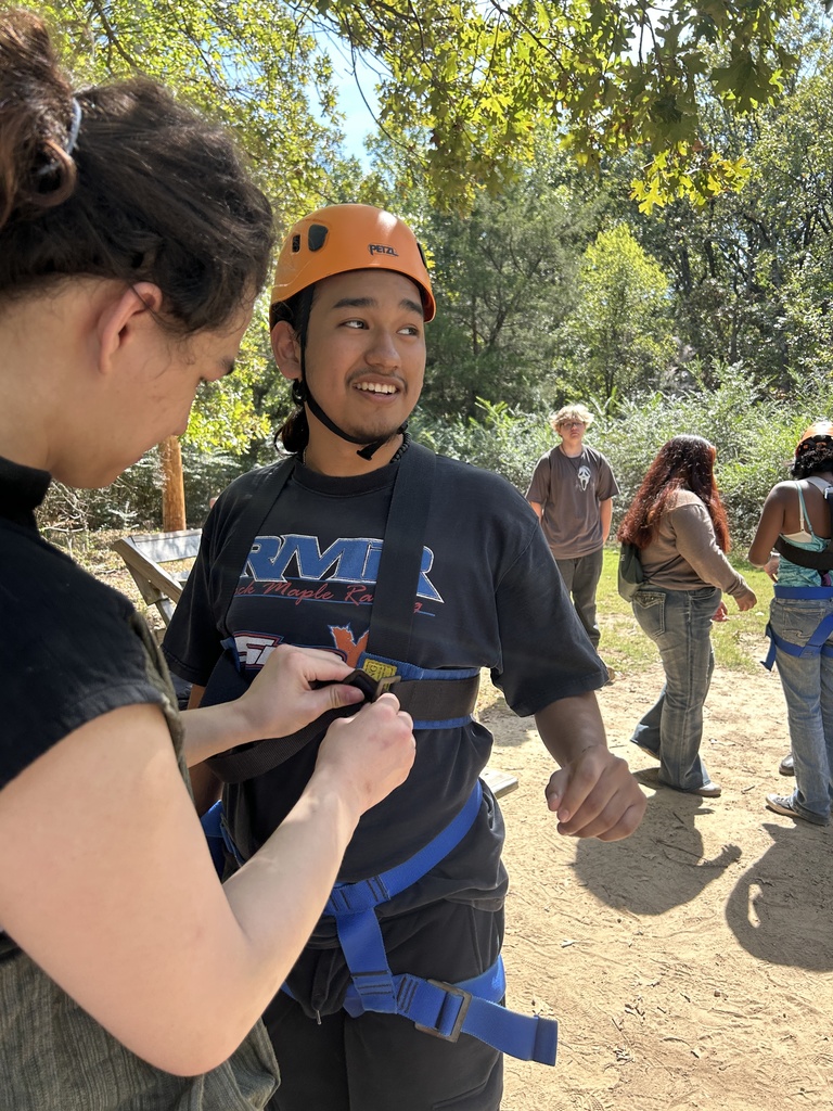 A student assisting another student with harness
