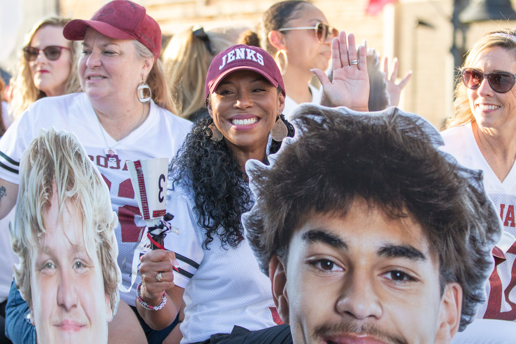 mom of football player float. mom holding a picture of her sons face and smiling