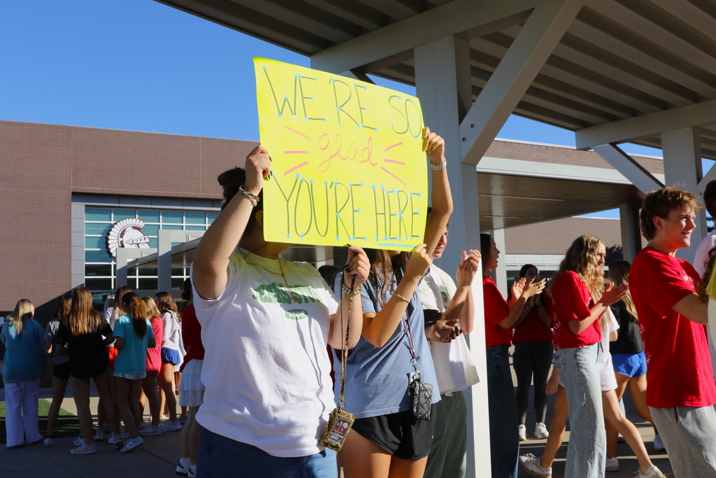 students holding sign reading "we're so glad you're here"