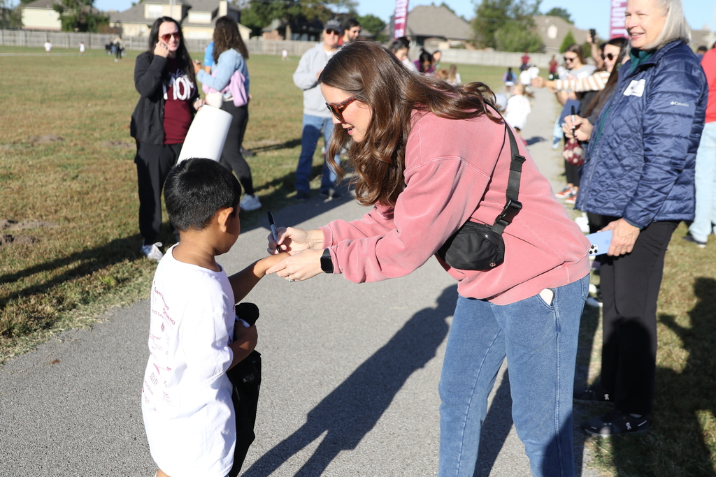 Parent volunteer marks student's hand for completing a lap during jog-a-thon