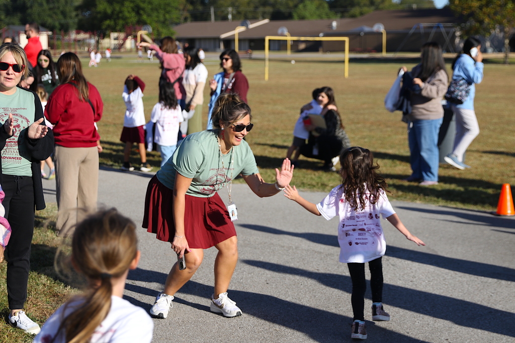 teacher high-fives student on track during jog-a-thon