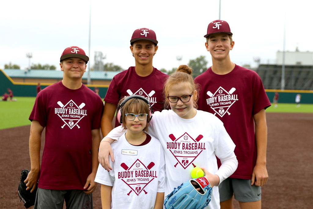 two girls playing buddy baseball game posing in front of group of baseball players