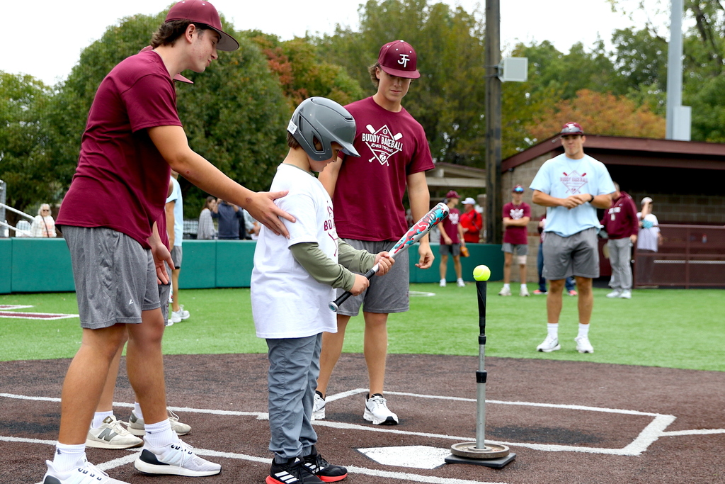 baseball players helping boy bat during buddy baseball