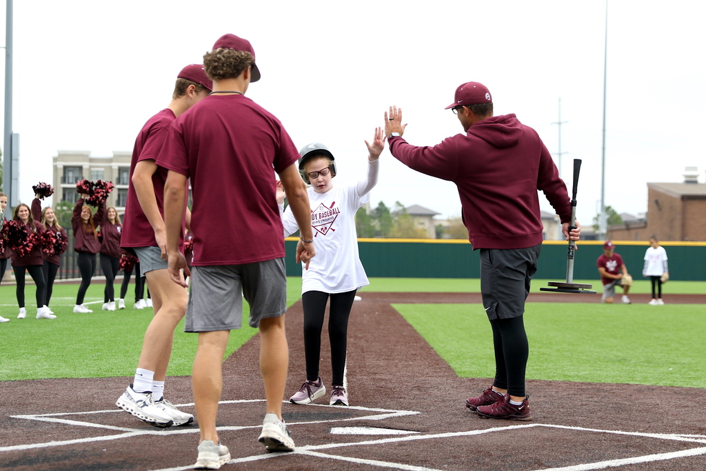 buddy baseball player high-fiving baseball coach while crossing home plate