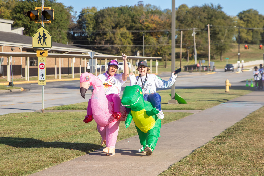 two teachers in blown up costumes one is a flamingo and the other is a dinosaur
