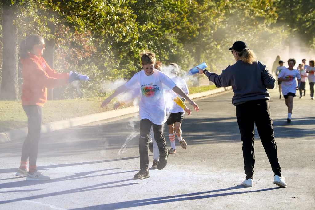 boy running through two people splashing colors
