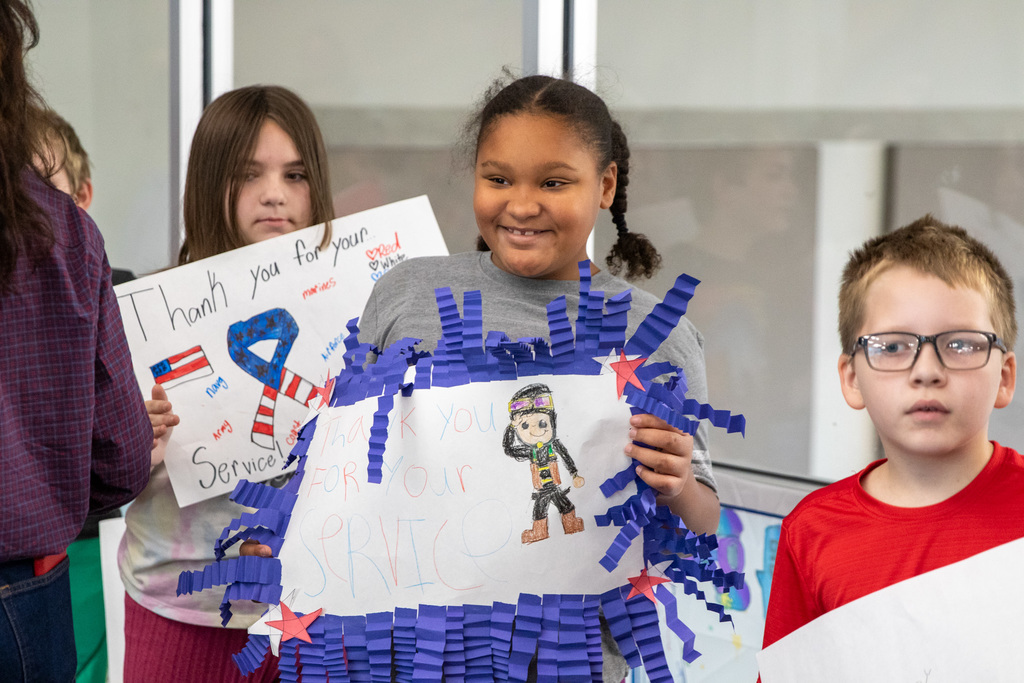 student holding up a handmade sign that says thank you for your service