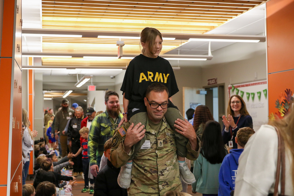 dad with daughter on his shoulders. he is in a army uniform and she is wearing a shirt that says army