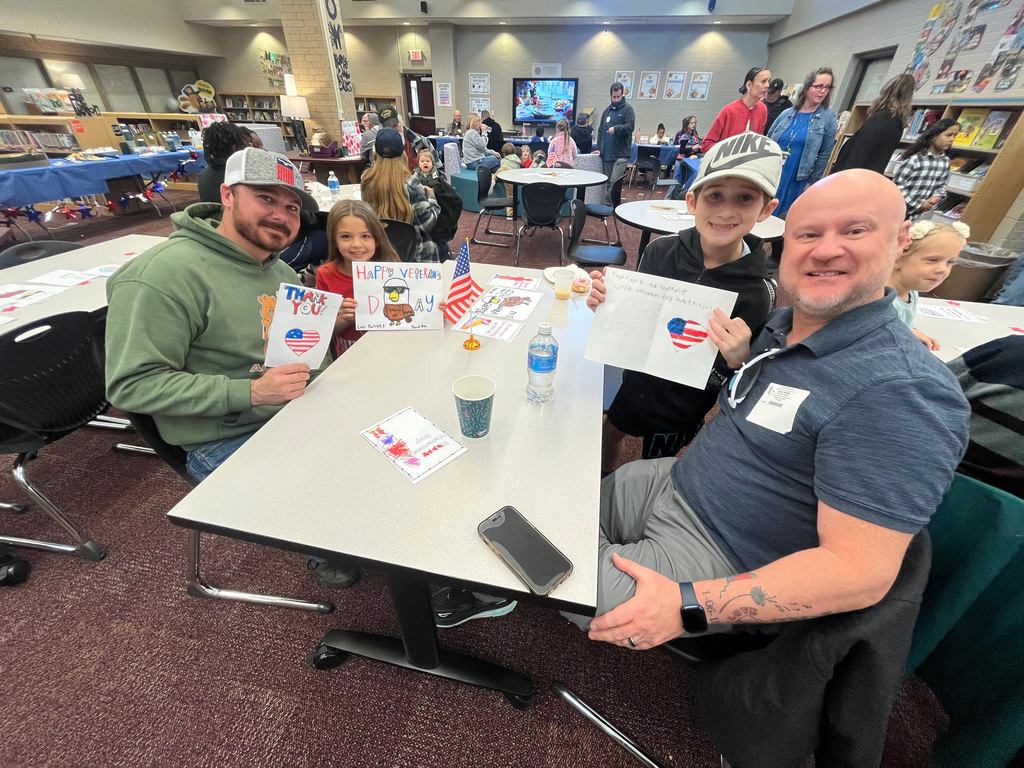 two students and their dads at a table eating breakfast