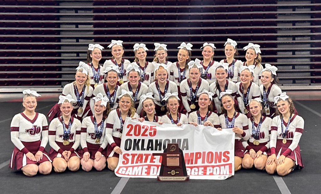 Jenks varsity pom squad posing with Game Day state championship trophy and banner