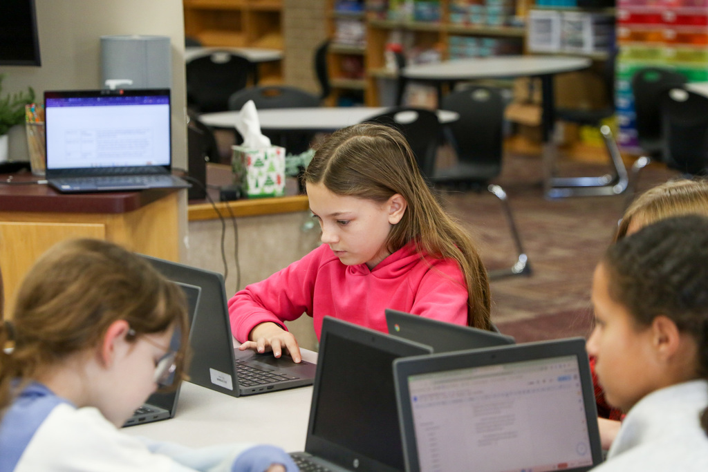 student typing her novel on a computer