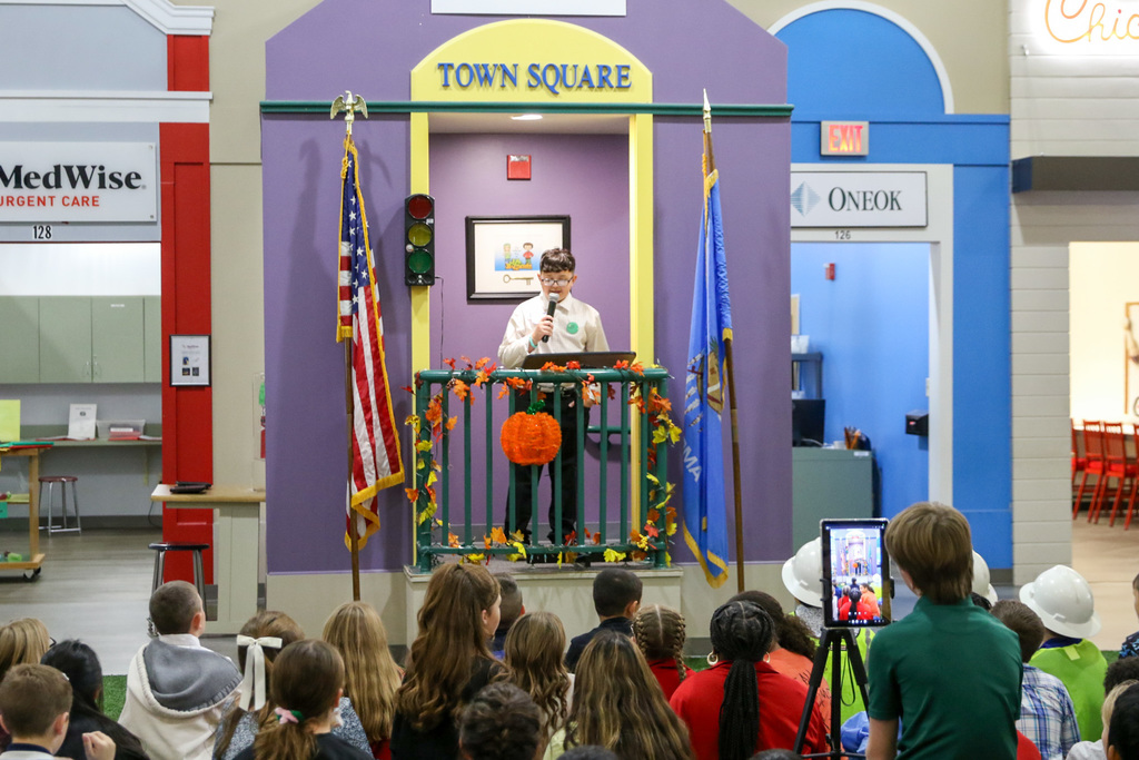 the mayor giving a speech in towns square at the town hall meeting