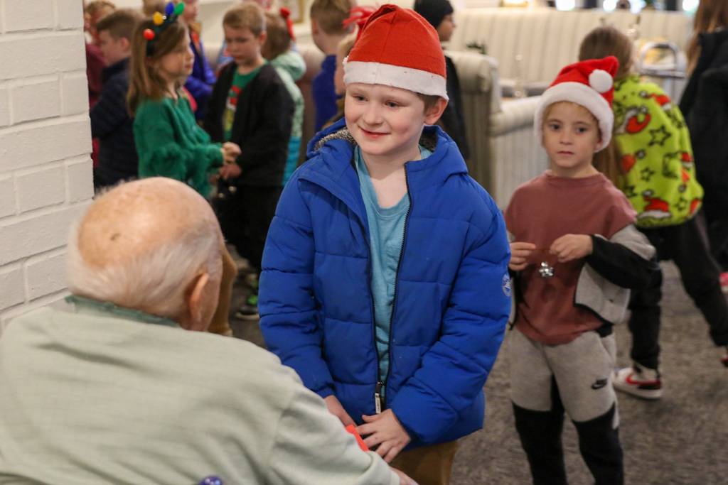 Boy with santa hat on talking to a resident