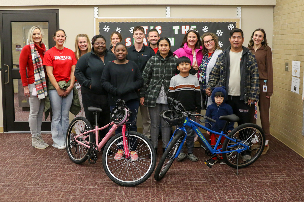 group photo with two bike recipients and their families, swerve members, and principals