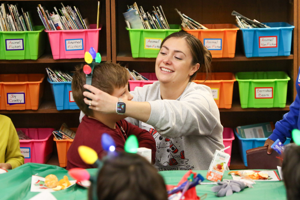 mom putting a holiday light headband on her son