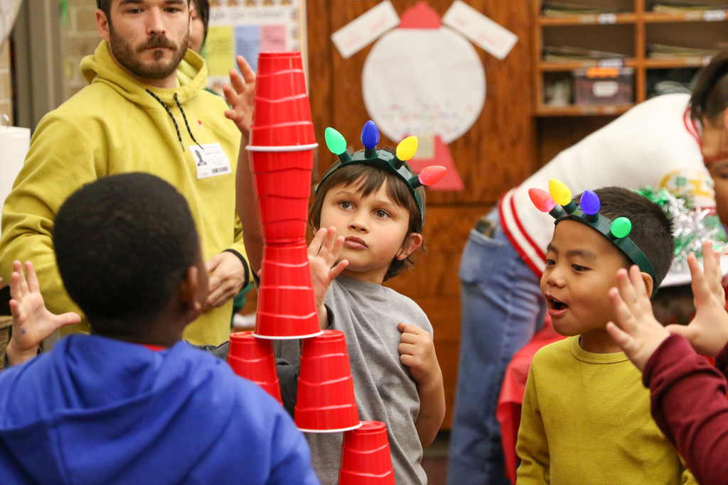 boys putting the top cup on their tall tower