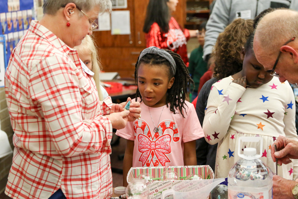 girl fascinated watching a woman make her a snowglobe