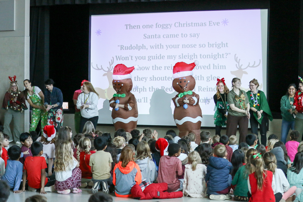 principals in gingerbread man costumes and teahers perfomring a dance
