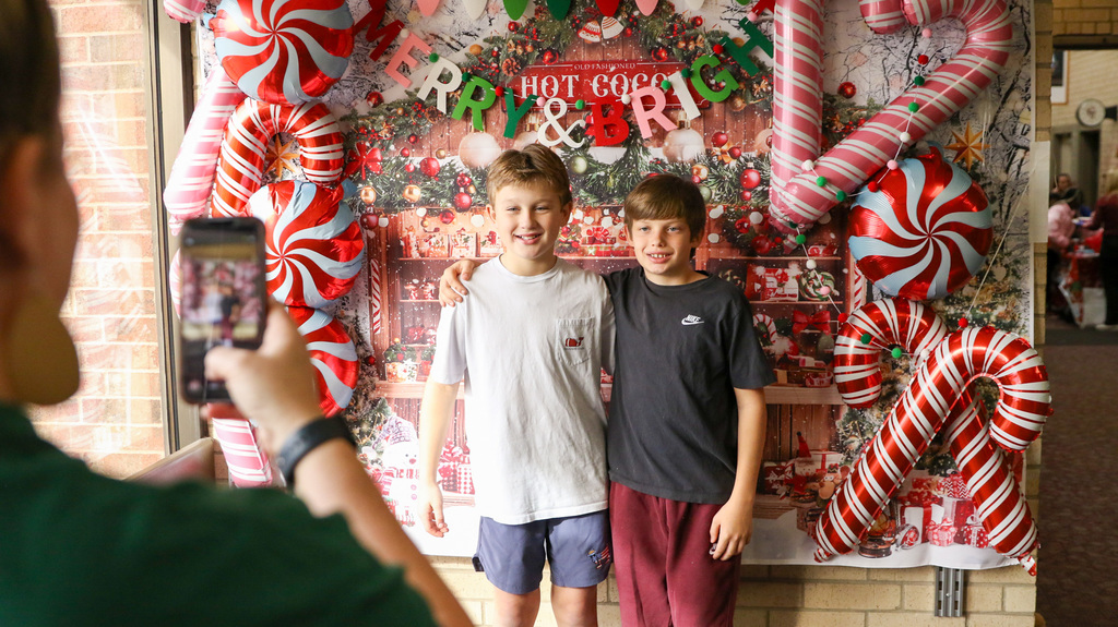 two students pose for a photo on a merry and bright photo background
