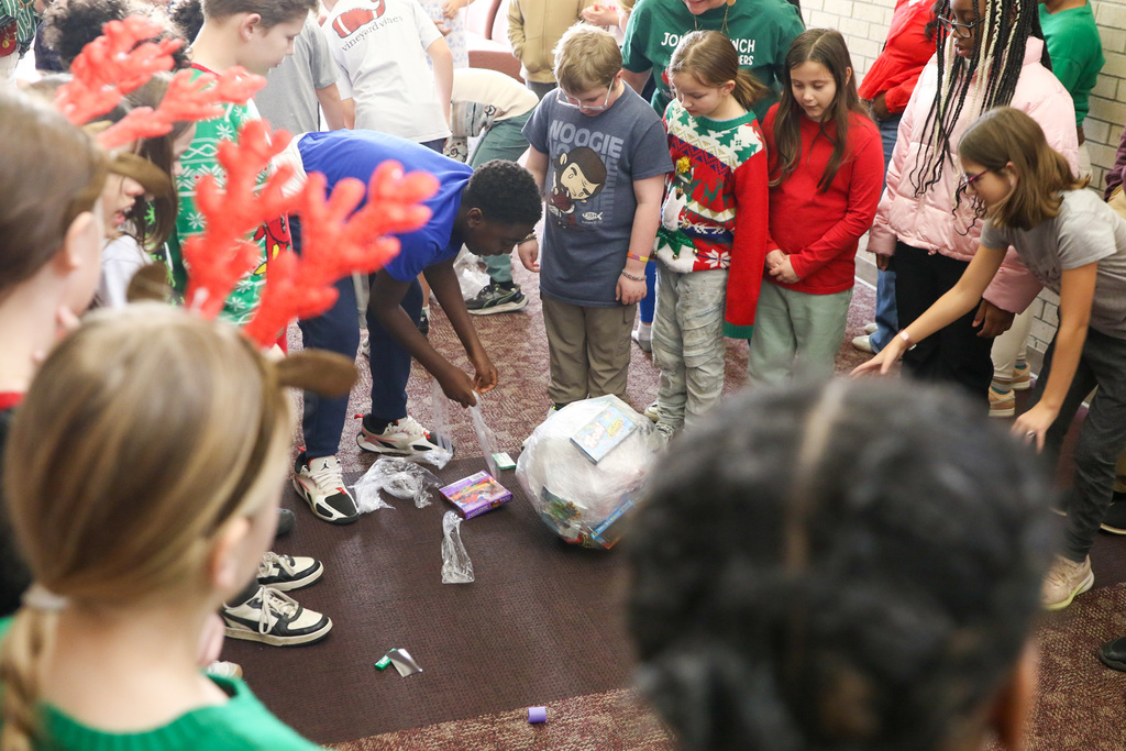 student playing a game of unwrapping a ball of plastic wrap with candy and toys inside