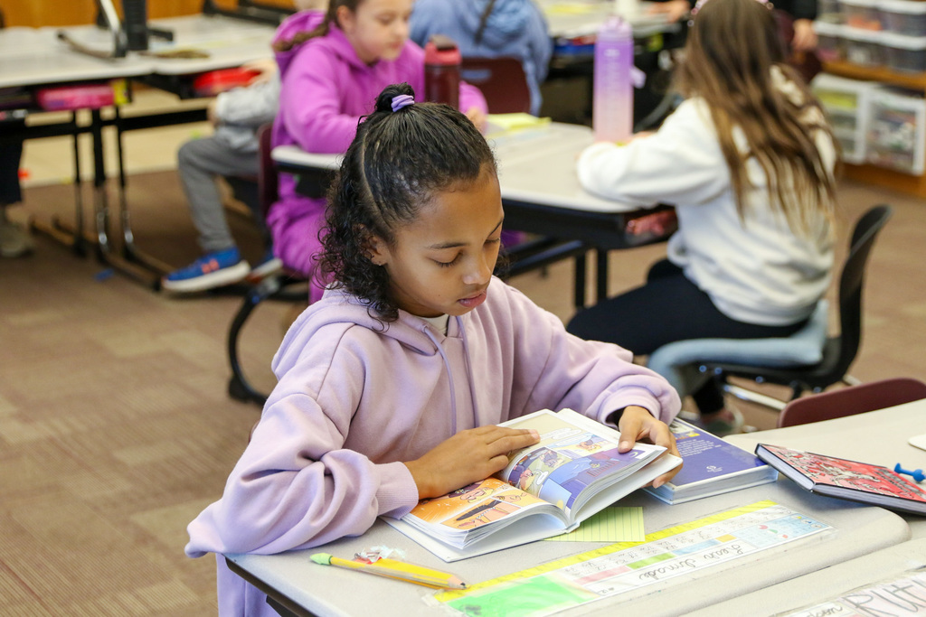 girl sitting at her desk reading a comic style book
