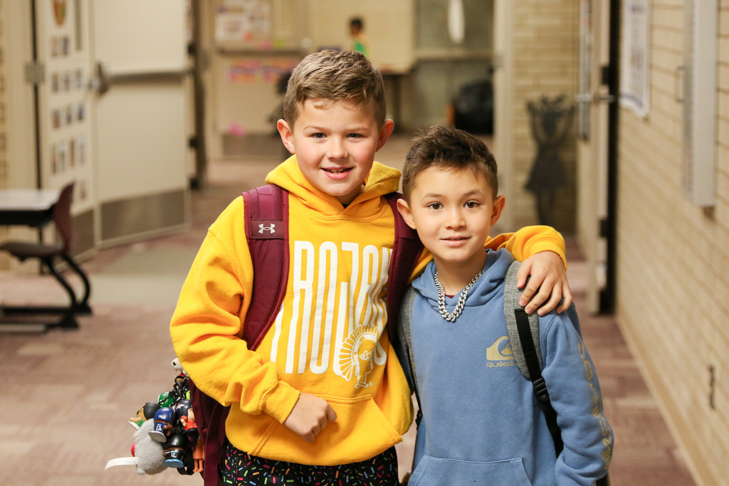 two boys in the hall with their arms around each other smiling for a photo 